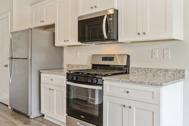 a kitchen with stainless steel appliances granite countertop white cabinets and stove