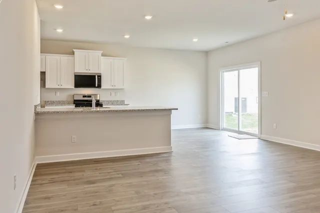 a view of a kitchen with kitchen island a sink wooden floor and black appliances