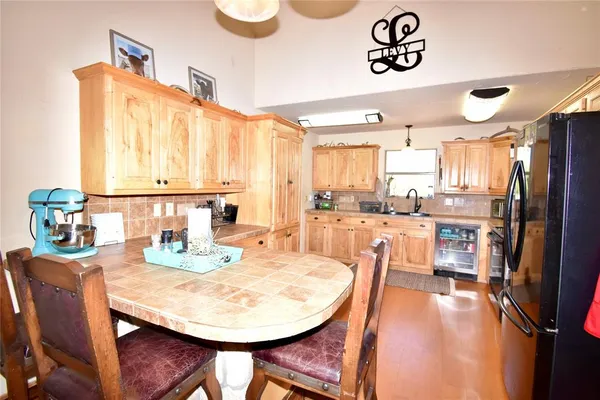 a dining room with stainless steel appliances kitchen island granite countertop a table chairs and a refrigerator