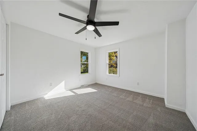 an empty room with a ceiling fan and a window