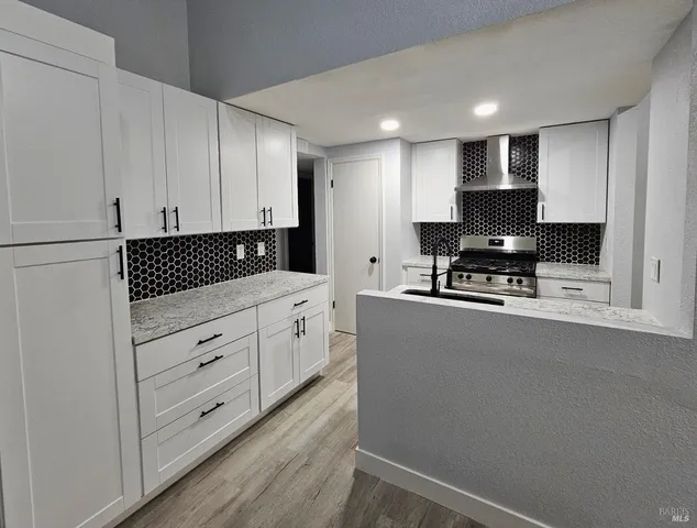 a kitchen with stainless steel appliances white cabinets and a stove top oven