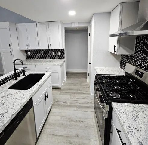 a kitchen with granite countertop a sink stove and cabinets