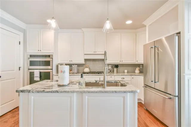 a kitchen with granite countertop a refrigerator a sink and white cabinets