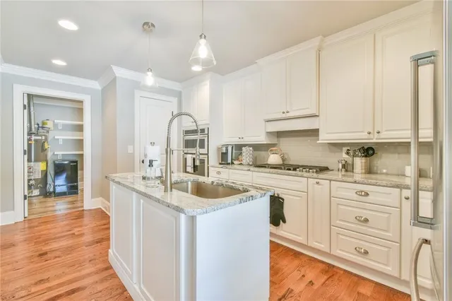 a kitchen with granite countertop a sink stainless steel appliances and white cabinets