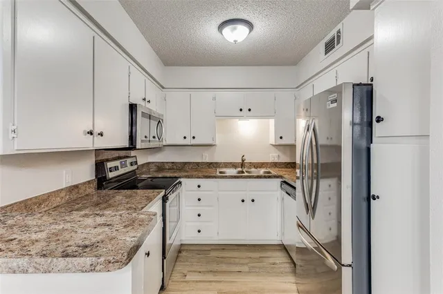 a kitchen with stainless steel appliances granite countertop a refrigerator and a stove