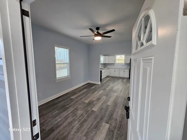 a view of empty room with wooden floor and fan