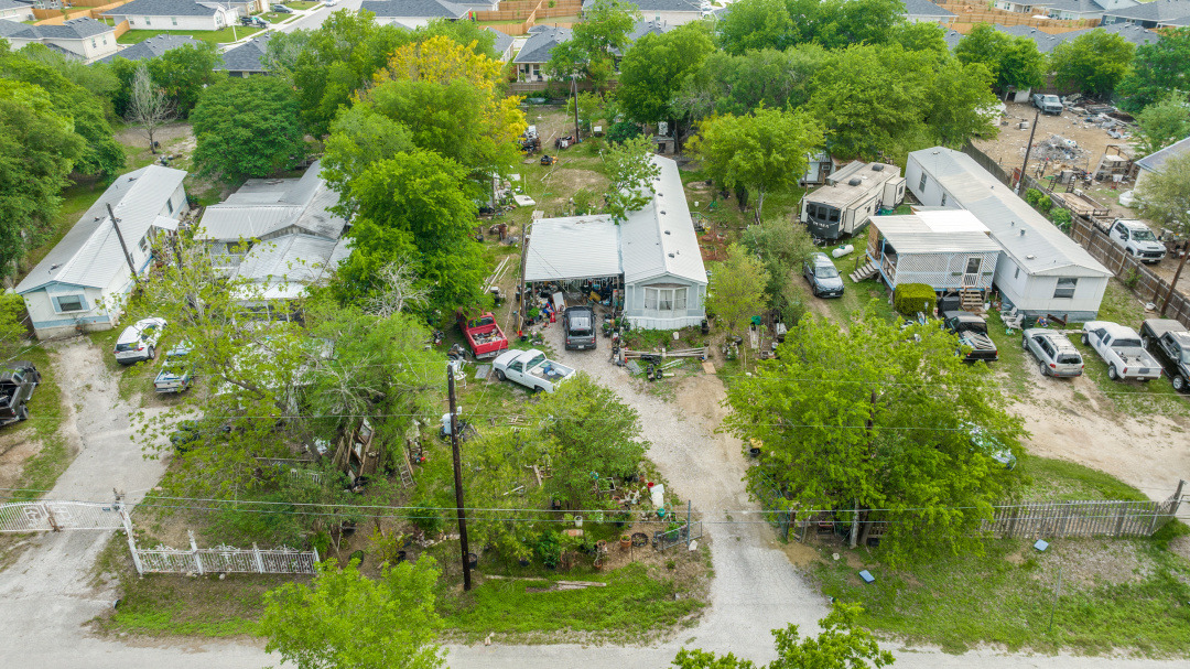 Aerial view of the property with a gravel driveway and surrounding mature trees