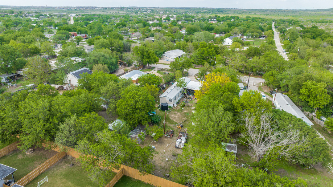 404 Quail Run Buda, TX 78610 - Photo 3 of 13 This aerial view showcases the property's surroundings, featuring a lush landscape with numerous mature trees