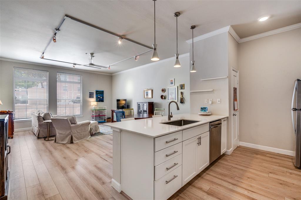 2305 Worthington Street, Unit 104 Dallas, TX 75204 - Photo 25 of 25 a kitchen with stainless steel appliances kitchen island hardwood floor sink stove and wooden cabinets