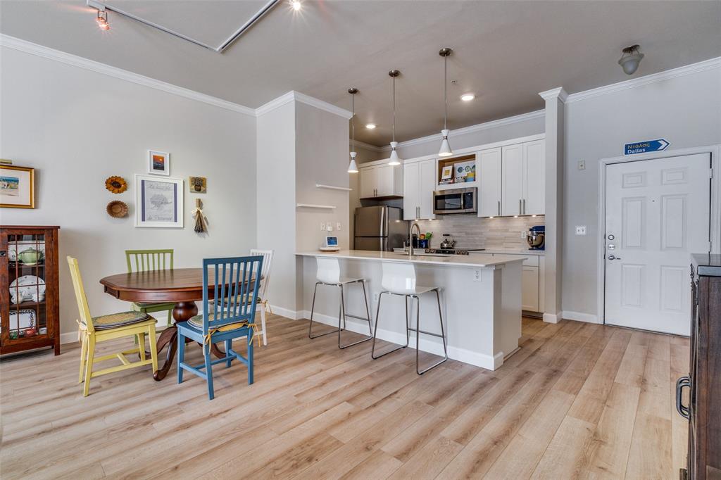 2305 Worthington Street, Unit 104 Dallas, TX 75204 - Photo 3 of 25 a kitchen with stainless steel appliances kitchen island granite countertop a table chairs and a refrigerator