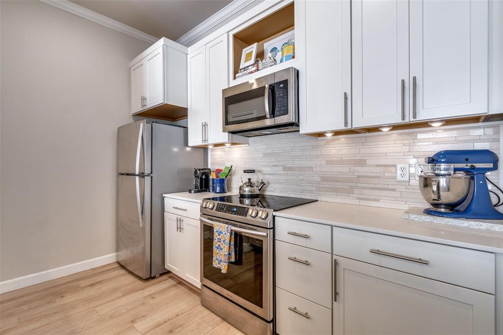 2305 Worthington Street, Unit 104 Dallas, TX 75204 - Photo 6 of 25 a kitchen with stainless steel appliances granite countertop white cabinets a stove a microwave and a refrigerator
