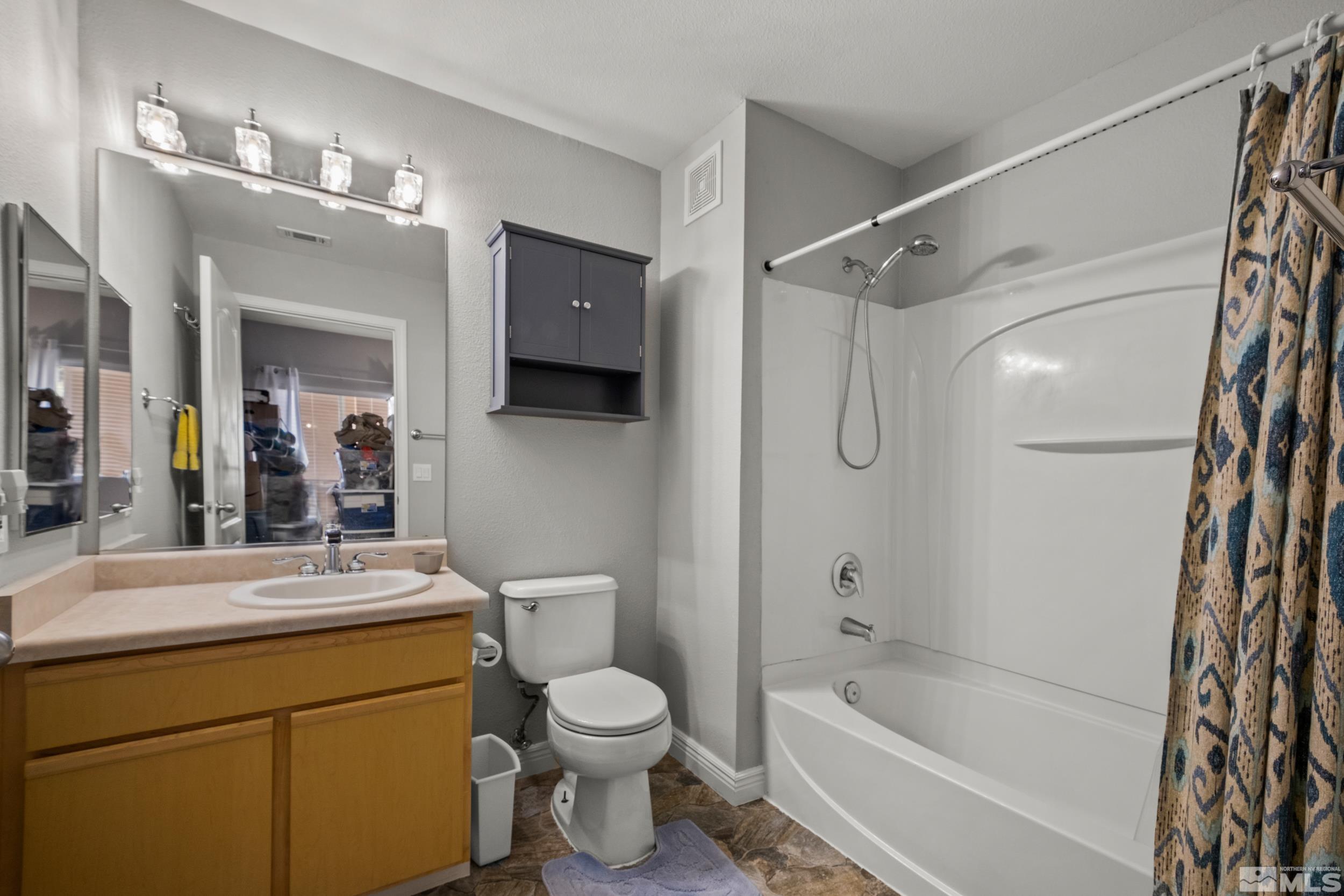 6850 Sharlands Avenue, Unit 1100 Reno, NV 89523 - Photo 14 of 26 a bathroom with a granite countertop sink a toilet a mirror a bathtub and shower