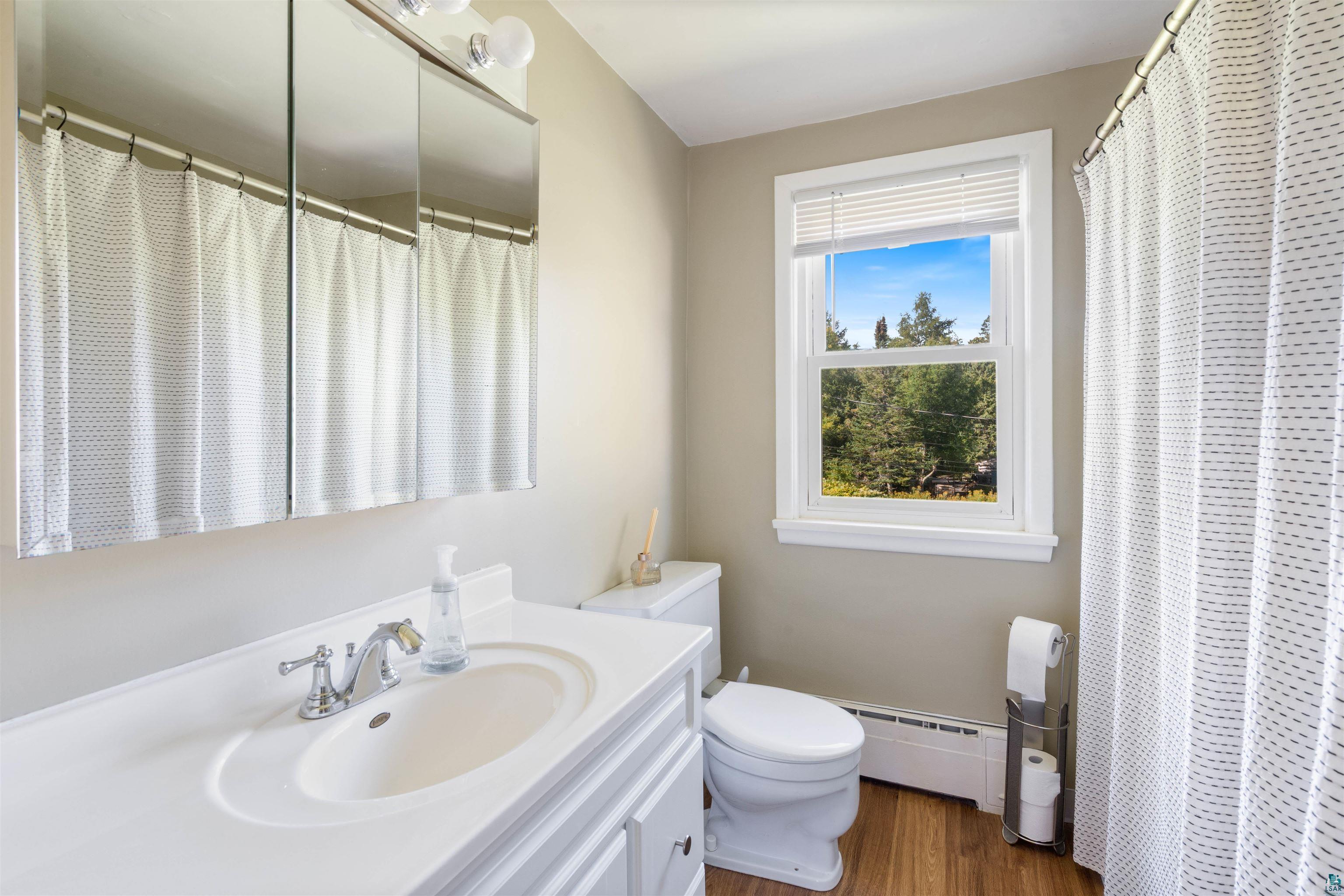 3715 Rendle Avenue Duluth, MN 55803 - Photo 12 of 20 Bathroom featuring a single vanity with an integrated sink, white cabinetry, chrome faucet, and a large window