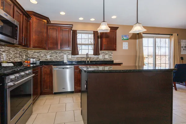 a kitchen with stainless steel appliances granite countertop a stove a sink and a microwave