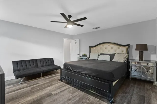 a bedroom with a bed a couch and a potted plant on dresser