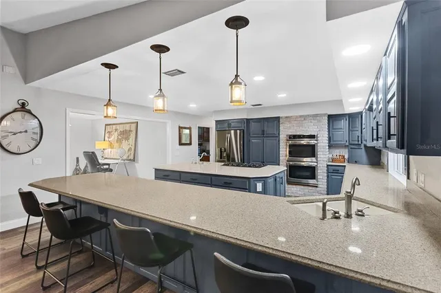 a kitchen with stainless steel appliances granite countertop a sink a stove and chairs