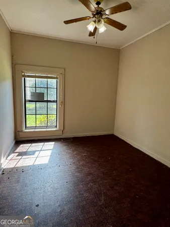 an empty room with a window and a fan