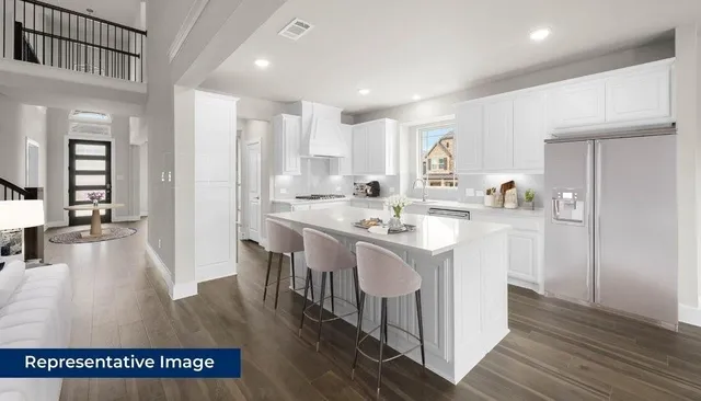 a kitchen with kitchen island a sink a stove a refrigerator and white cabinets with wooden floor