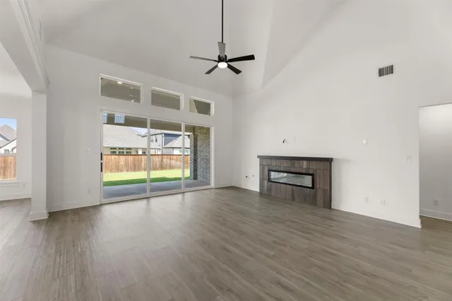 an empty room with wooden floor fireplace and windows
