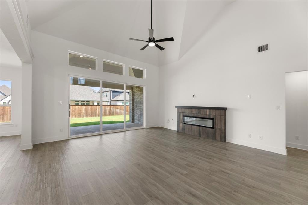 9621 Chesney Drive Forney, TX 75126 - Photo 19 of 36 an empty room with wooden floor fireplace and windows