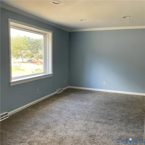 an empty room with wooden floor chandelier and windows