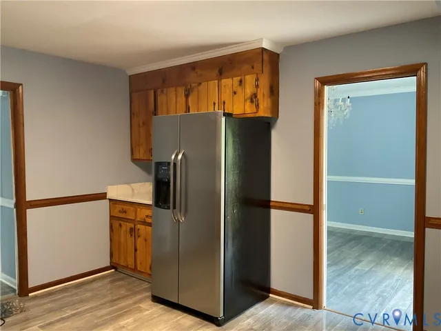 an empty room with wooden floor chandelier and windows