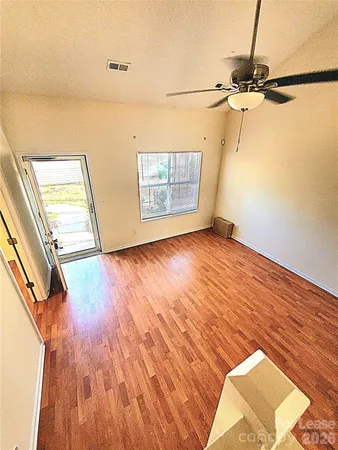 a view of an empty room with a window and wooden floor