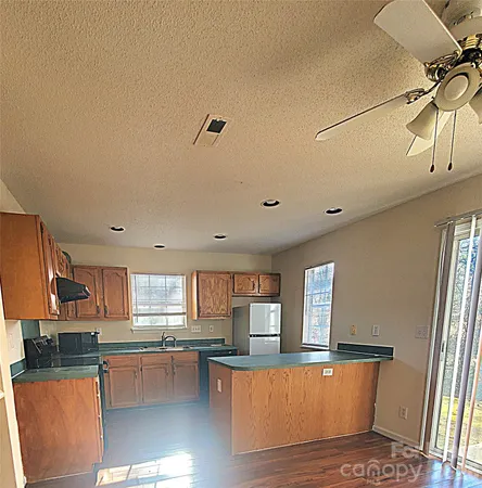 a kitchen with stainless steel appliances granite countertop a refrigerator a sink dishwasher a stove and white countertops with wooden floor