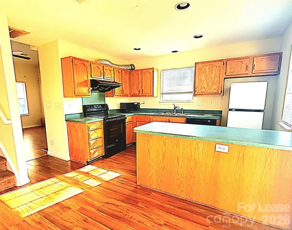 a kitchen with stainless steel appliances granite countertop a sink cabinets and wooden floor