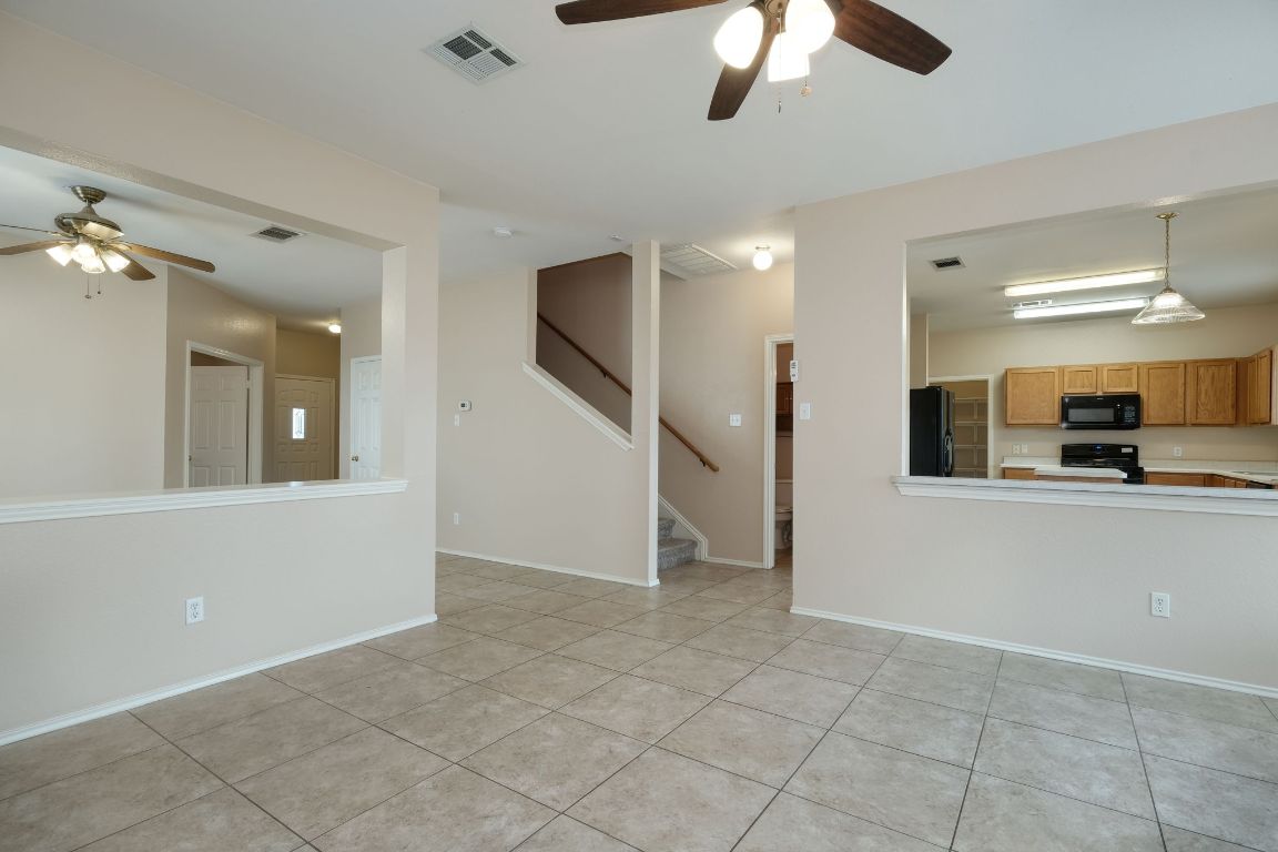 116 Rio Grande Drive Kyle, TX 78640 - Photo 3 of 13 Unfurnished living room with ceiling fan, light tile patterned flooring, and stairway