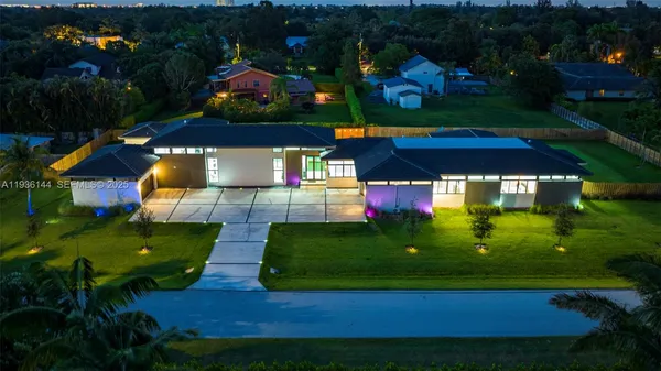a view of a house with a big yard potted plants and large tree