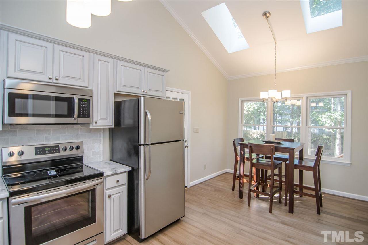 109 Boxford Road Morrisville, NC 27560 - Photo 8 of 27 a kitchen with refrigerator cabinets dining table and wooden floor