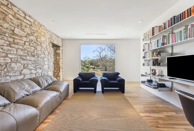 a living room with furniture a flat screen tv and a floor to ceiling window