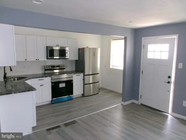 a kitchen with granite countertop a refrigerator and a stove top oven