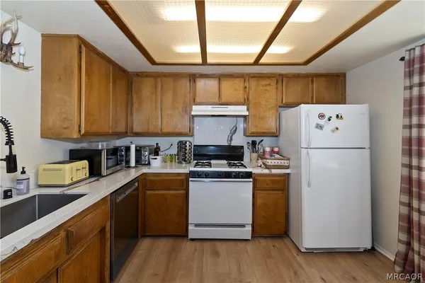 a kitchen with a refrigerator a stove and wooden floors