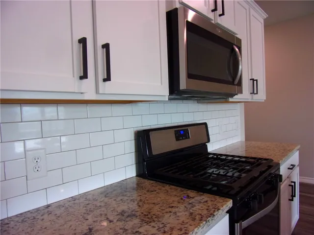 a kitchen with granite countertop a stove and a microwave