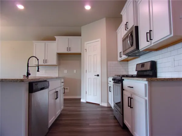 a kitchen with kitchen island granite countertop a sink cabinets and wooden floor