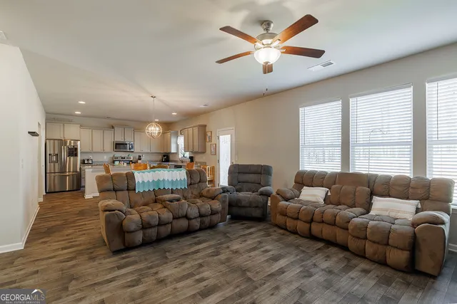 a living room with furniture kitchen view and a large window