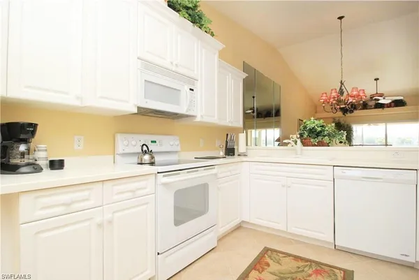 a kitchen with stainless steel appliances kitchen island granite countertop white cabinets and white appliances