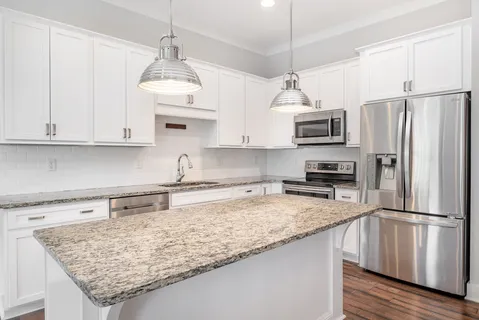 a kitchen with kitchen island granite countertop a sink stainless steel appliances and white cabinets