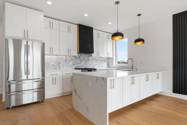 a kitchen with stainless steel appliances granite countertop a refrigerator a sink a stove and a wooden floors