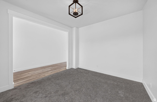 1002 West Temple Rim Lane Payson, UT 84651 - Photo 9 of 68 Spacious room featuring plush gray carpeting, white walls, white baseboards, and a modern geometric ceiling light fixture