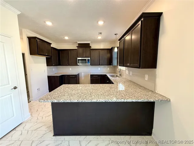 a large kitchen with kitchen island granite countertop a refrigerator a sink a stove and black cabinets