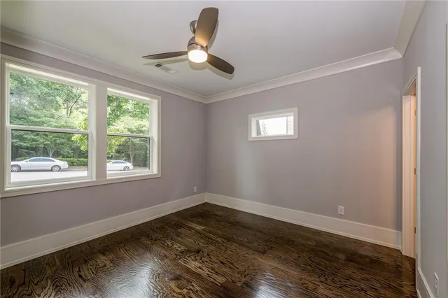a view of empty room with wooden floor and fan