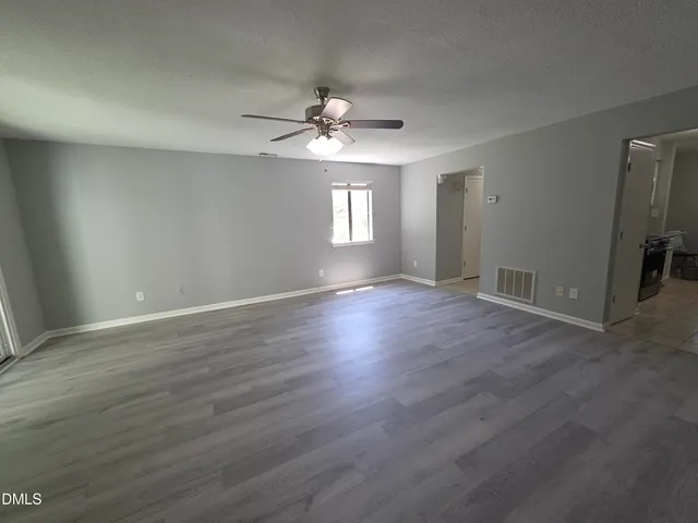 a view of an empty room with window and wooden floor