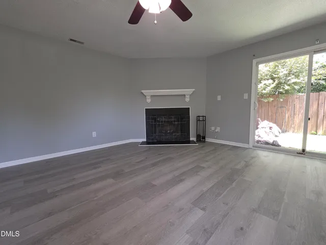 an empty room with wooden floor chandelier and windows
