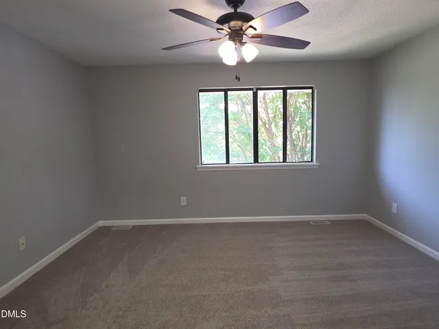an empty room with a window and a fan