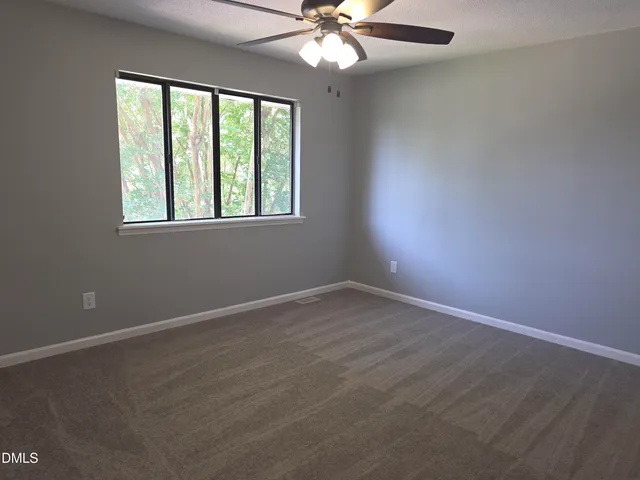 an empty room with windows and fan