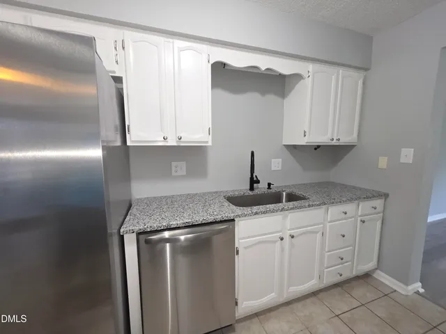 a kitchen with granite countertop white cabinets and a sink