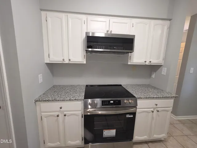 a kitchen with stainless steel appliances granite countertop white cabinets and a stove